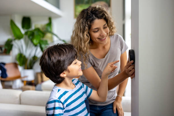 Happy Houston mother and child adjusting their home's smart thermostat, showcasing family-friendly energy efficiency and cost-effective temperature control.
